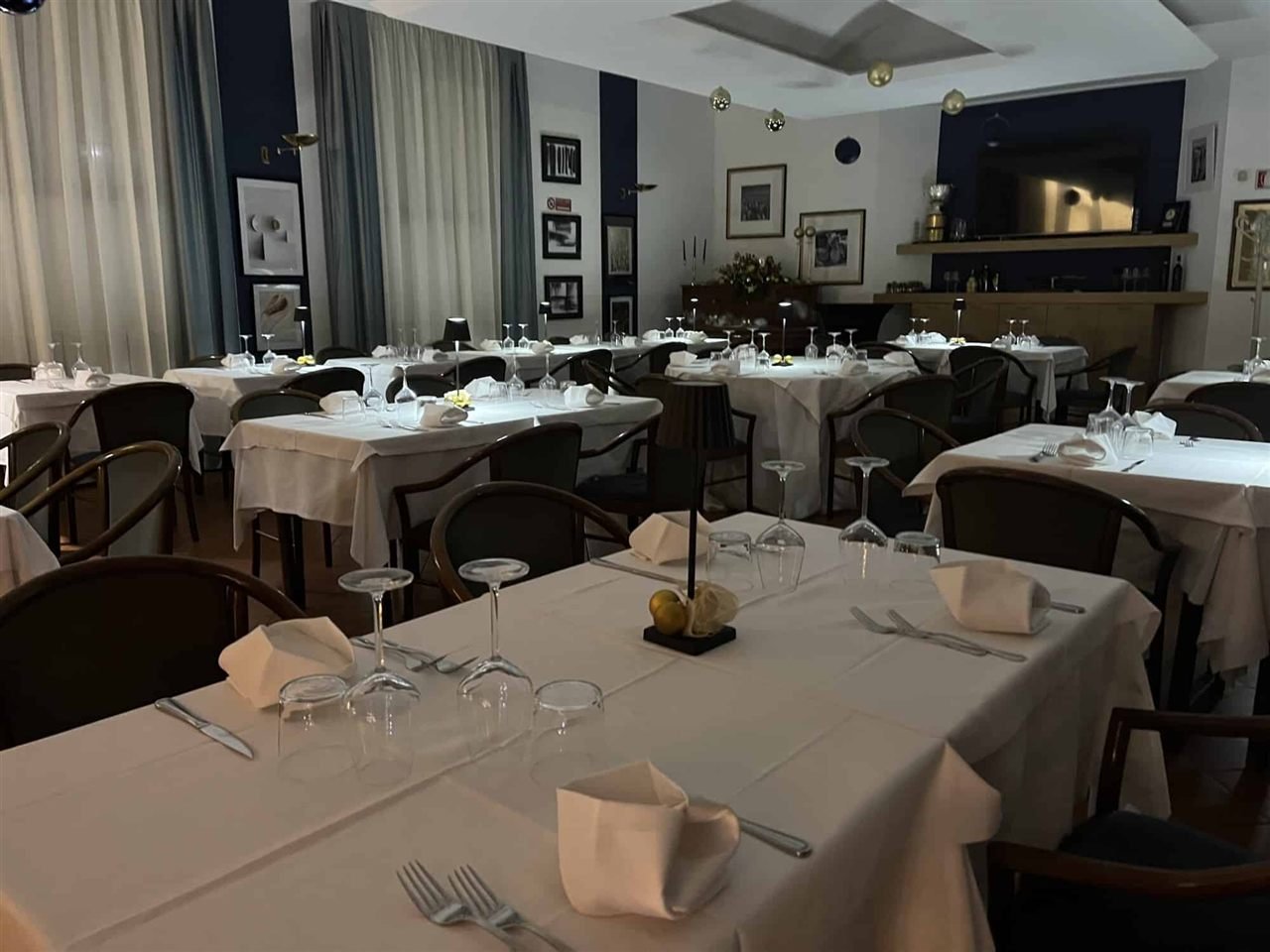La sala interna del ristorante, tavoli apparecchiati con tovaglie bianche e le pareti blu del circolo